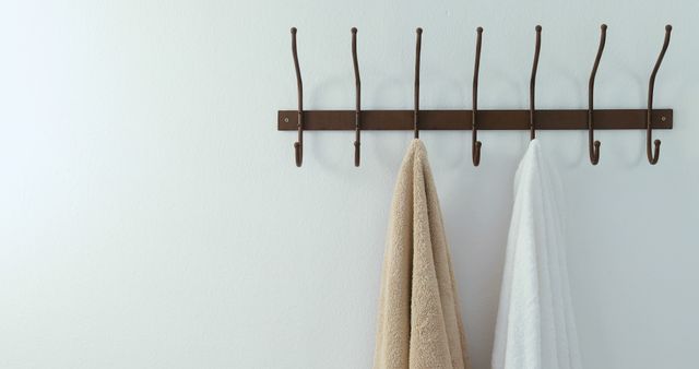 Beige and white towels hanging on brown hanger rack, copy space. Towel, hanging and hanger rack concept, unaltered.