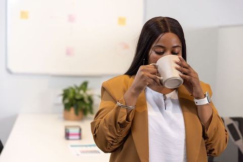 African american professional woman sipping coffee in modern office during work break