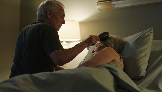 Senior man brushing hair of sleeping partner in cozy bedroom showing gentle eldercare