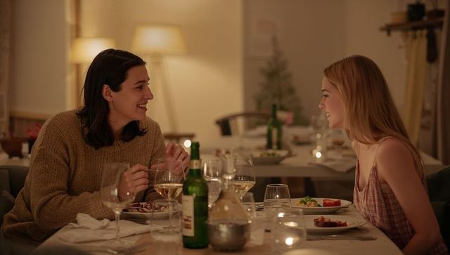 Candlelit dinner two friends sharing wine and conversation at cozy home dining table