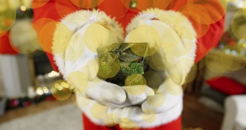 Santa holding small gift box with glowing belle decoration