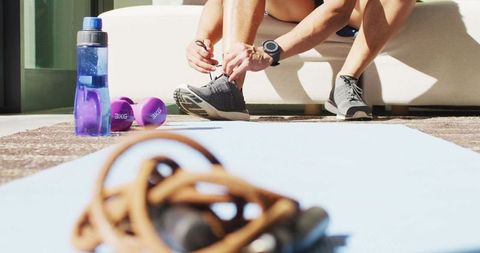Athlete Tying Shoes for Home Workout with Fitness Equipment