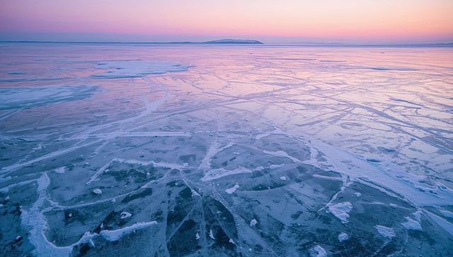 Tranquil frozen lake under pastel sunset sky