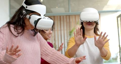 Diverse women exploring virtual reality headsets in office collaborating and training