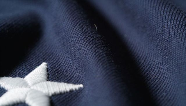 Macro navy ribbed knit fabric with embroidered white star, lint and soft weave texture