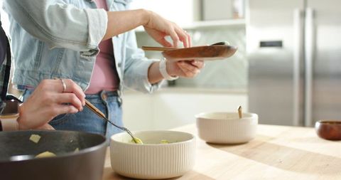 Women preparing and serving homemade food at bright kitchen counter with ribbed ceramic bowls
