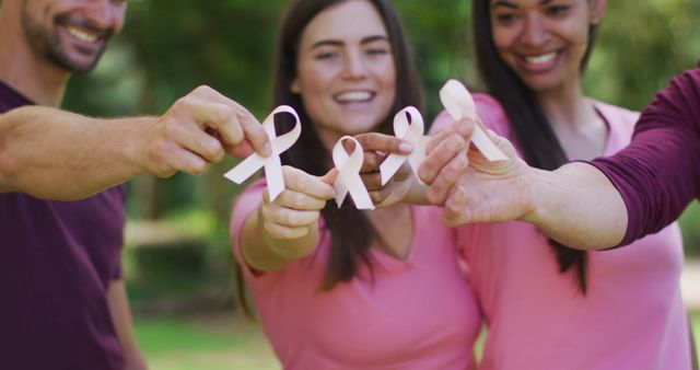 A diverse group of individuals holding and presenting pink ribbons, symbolizing breast cancer awareness. Ideal for topics related to health initiatives, cancer support groups, charity events, community solidarity, and fundraising campaigns.