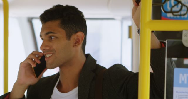 Young man smiling while talking on phone in public transport - Download Free Stock Images Pikwizard.com