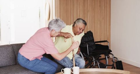 Senior couple assisting mobility with cane in cozy living room