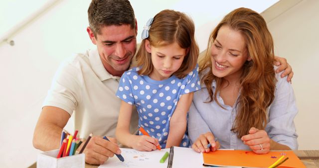 A close-up showing a happy family. Parents are helping their young daughter with her homework. The girl is attentively drawing while both parents look on supportively, creating a warm and nurturing atmosphere. Perfect for illustrating concepts related to family bonding, education, parental involvement, and home learning environments.