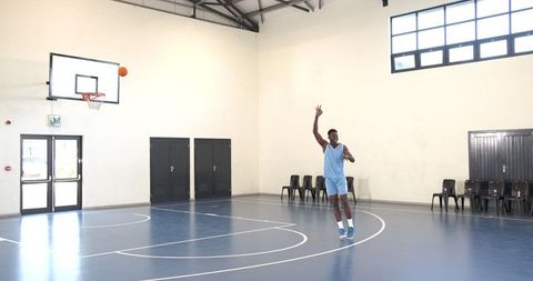 Basketball Player Practicing Three-Point Shot in Gym