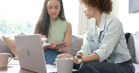 Two African American Women Collaborating on Laptop in Bright Natural-Light Home Workspace