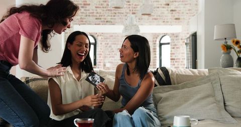 Excited friends celebrating pregnancy announcement at home
