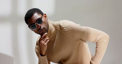 Stylish man in minimalist setting wearing sunglasses and sweater