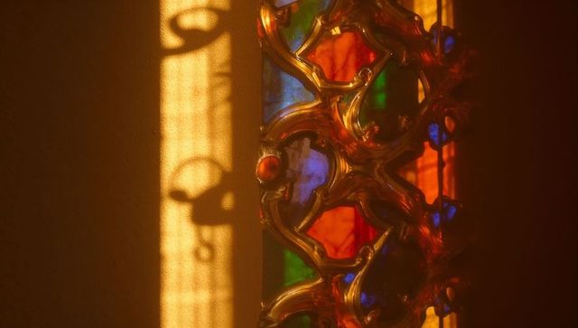 Vibrant stained glass plays colorful shadows on wall