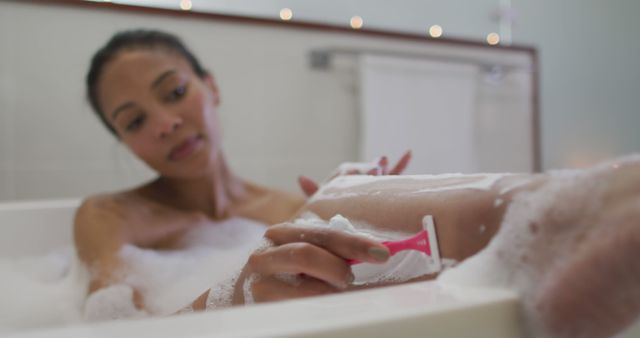 Biracial woman taking a bath shaving her legs - Download Free Stock Photos Pikwizard.com