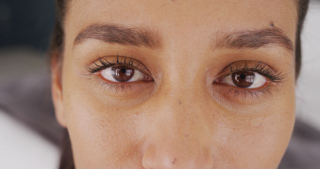 Close-up view of a woman's eyes highlighting her brown eyes, perfectly groomed eyebrows, and long eyelashes. This visual is ideal for beauty and skincare promotions, makeup tutorials, or articles focused on eye care. It can also be used in advertisements emphasizing natural beauty or personal care routines.