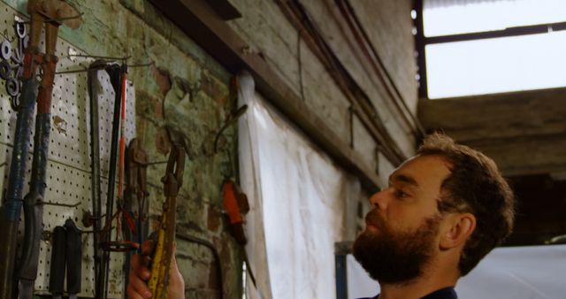 Bearded man organizing tools in workshop - Download Free Stock Images Pikwizard.com