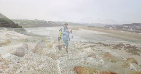 Senior Hiker Navigating Wet Coastal Rocks with Trekking Poles