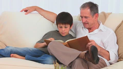 Grandfather and Grandson Bonding While Reading on Couch
