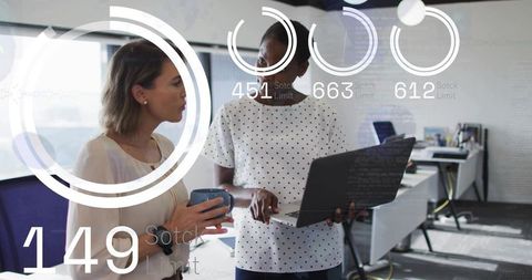 Female colleagues collaborating over laptop and coffee with digital hud analytics overlay