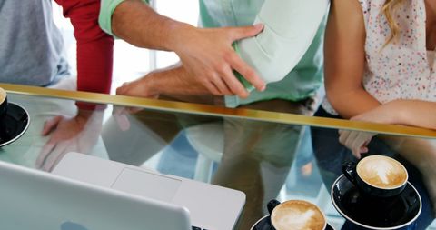 Friends Enjoying Coffee and Laptop Interaction at Cafe Table