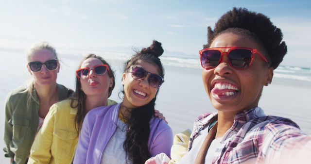 Happy group of diverse female friends having fun, taking selfie with smartphone at the beach. holiday, freedom and leisure time outdoors.