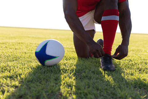 Transparent focus on rugby player tying shoes on field