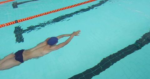 Male swimmer gliding underwater in competition pool