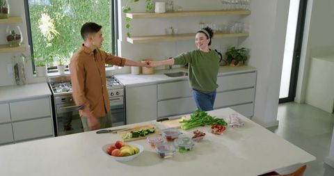 Happy Couple Dancing in Modern Kitchen with Fresh Produce