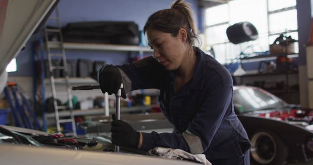 Female mechanic using a wrench to repair a car at a car service station. automobile repair service