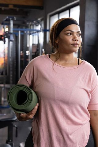 African american woman holding yoga mat at gym practicing mindful fitness routine