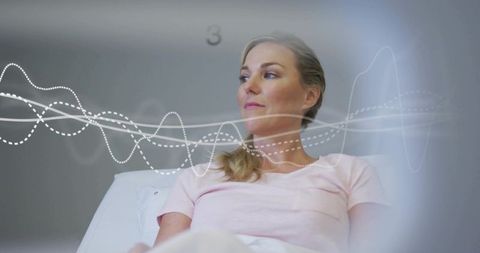 Reclining woman on exam table with diagnostic waveform overlay representing patient monitoring