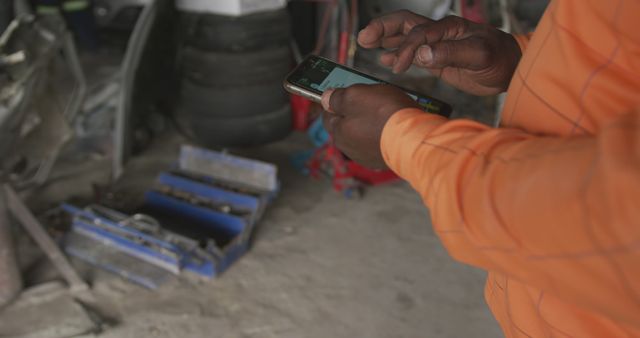 Mechanic in Orange Jacket Using Smartphone in Workshop - Download Free Stock Images Pikwizard.com