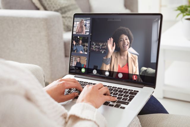 Multiracial colleagues waving hands on video call to caucasian businesswoman working at home. unaltered, work from home, business, wireless technology, working, teamwork and office concept.