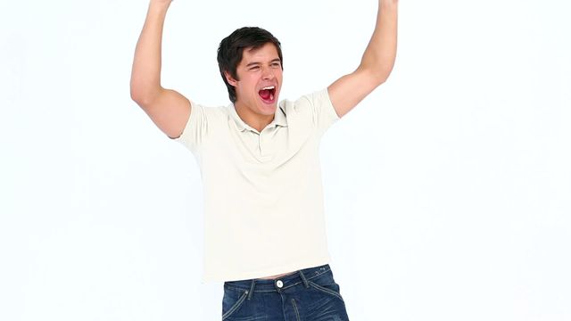 Man is expressing excitement and triumph with arms raised and shouting. Video is suitable for use in themes related to victory, success, achievement, and personal triumph. It can be used on motivational posters, in advertisements promoting positive outcomes, or as editorial content highlighting human emotion and celebration.