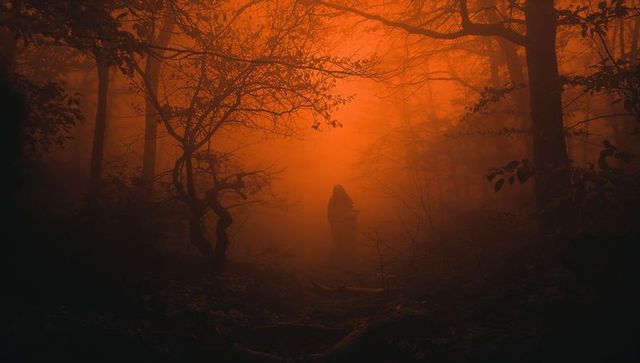 Mysterious cloaked figure in enigmatic orange mist