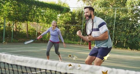 Enthusiastic tennis partners celebrating winning point on outdoor court