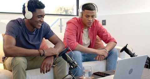 Two young men recording podcast with microphones and headphones
