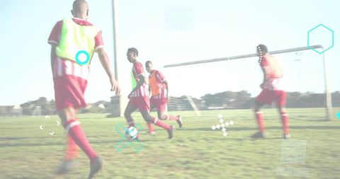 Youth soccer players converging on ball near goalpost wearing neon bibs and red jerseys