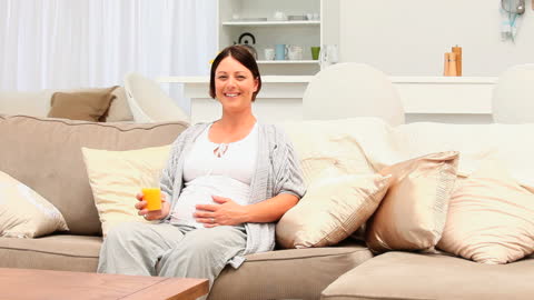 Pregnant Woman Smiling While Drinking Orange Juice