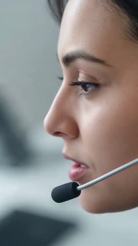 Vertical video customer support agent speaking into headset at call center desk