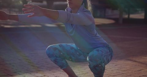 Woman squatting on urban plaza wearing patterned leggings and long-sleeve top