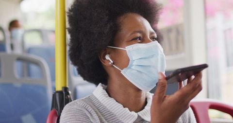 African American Woman On Bus Using Smartphone Wearing Face Mask