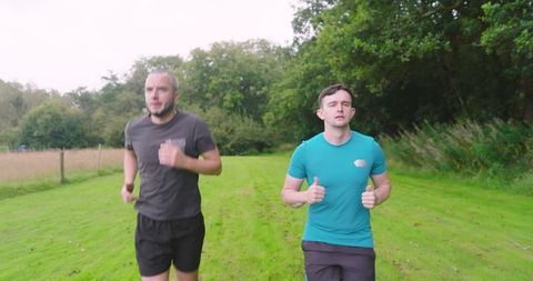 Young men jogging through open green park inspiring fitness journey