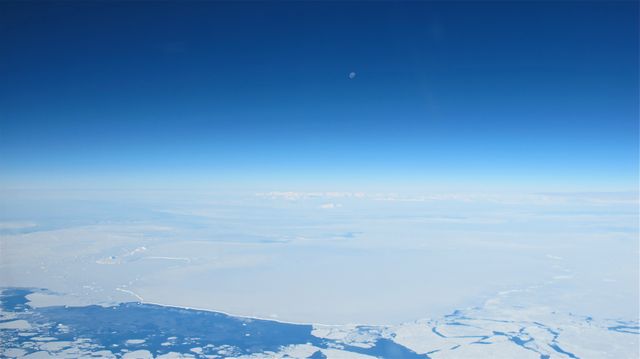 The moon is seen over the vast expanse of the Antarctic Peninsula during NASA's Operation IceBridge, an airborne mission to study Earth's polar ice. Photographed from a DC-8 aircraft on October 25, 2012. This stunning panoramic view showcases the isolation and beauty of the Antarctic landscape, making it a perfect illustration for topics related to Earth's polar regions, climate research, or scientific exploration.