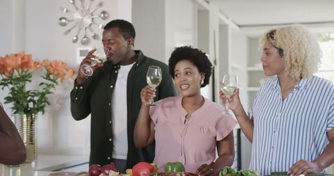 Friends Enjoying Wine While Cooking in Bright Kitchen