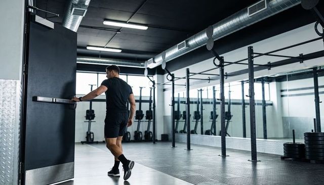 Athlete walking into spacious industrial gym with squat racks and stacked plates