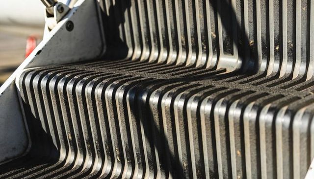 Close-up of ribbed metal stair treads with dirty grooves, steel bracket detail