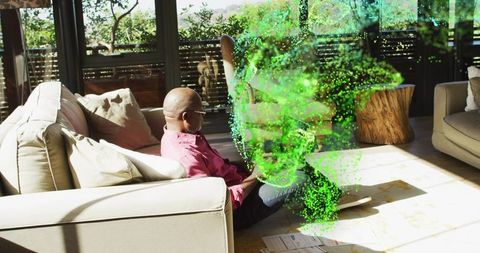 Elder man sitting in sunlit living room watching green holographic projection of data
